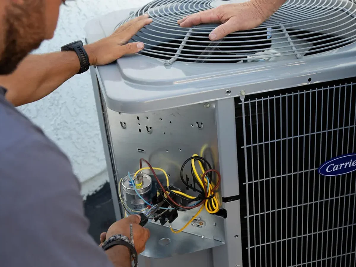 Technician checking the capacitor and wiring inside a residential air conditioning condenser